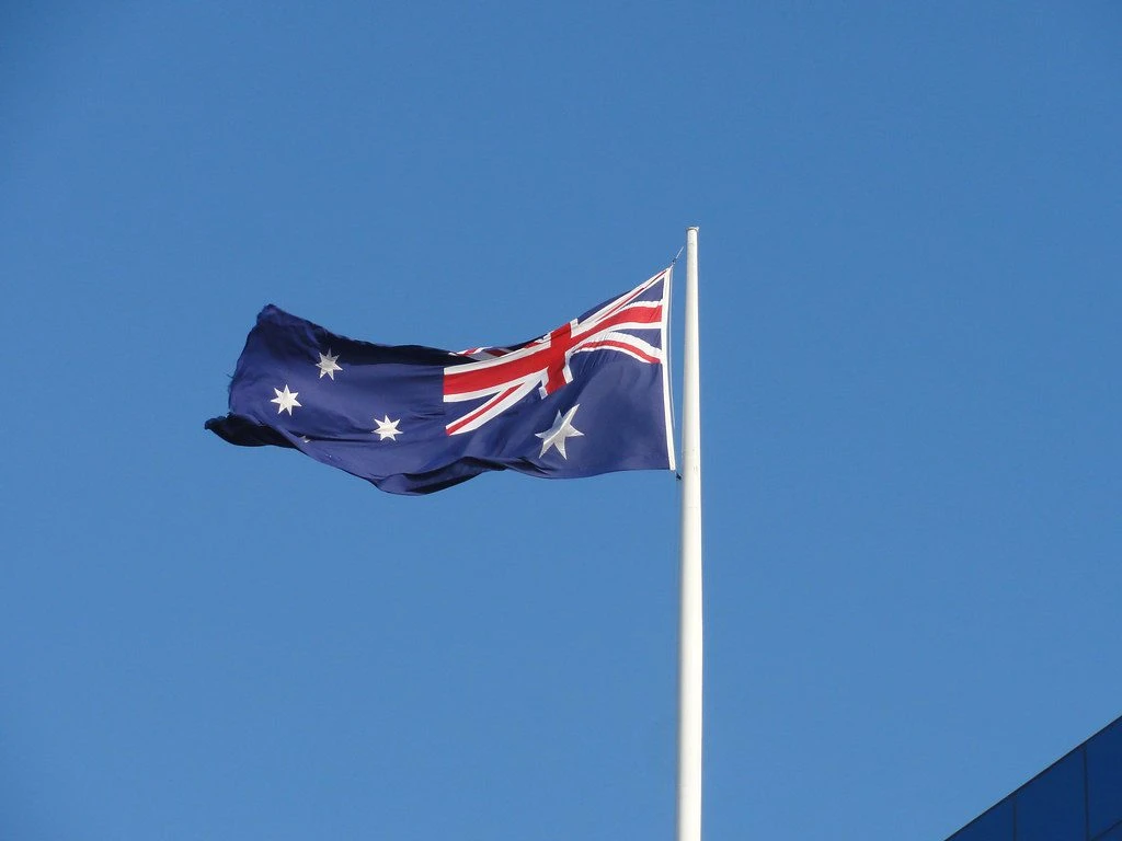 Australian flag waving against blue sky on white pole, symbolising ACMA crackdown on illegal gambling sites