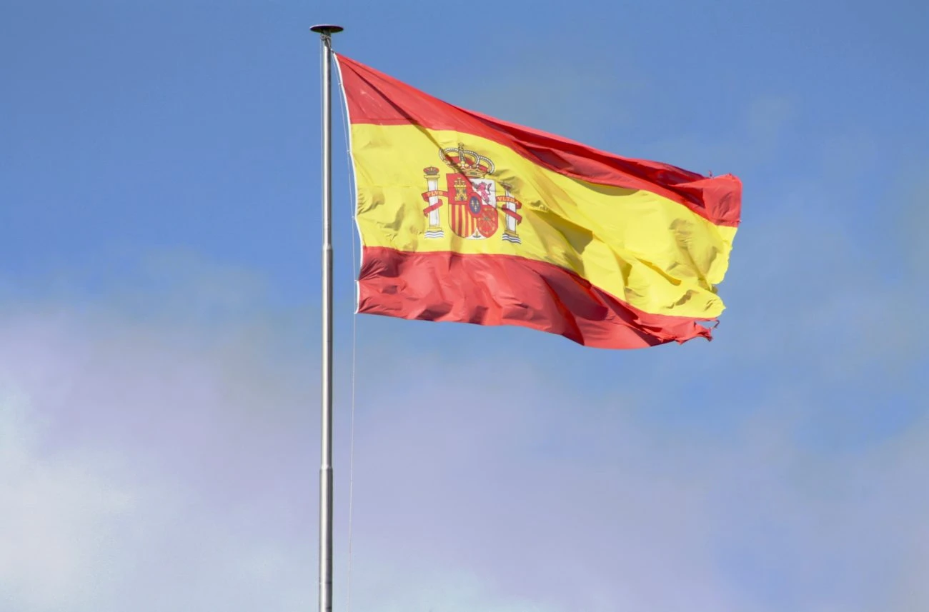 Spain flag waving against blue sky as country launches joint deposit limits for online gambling